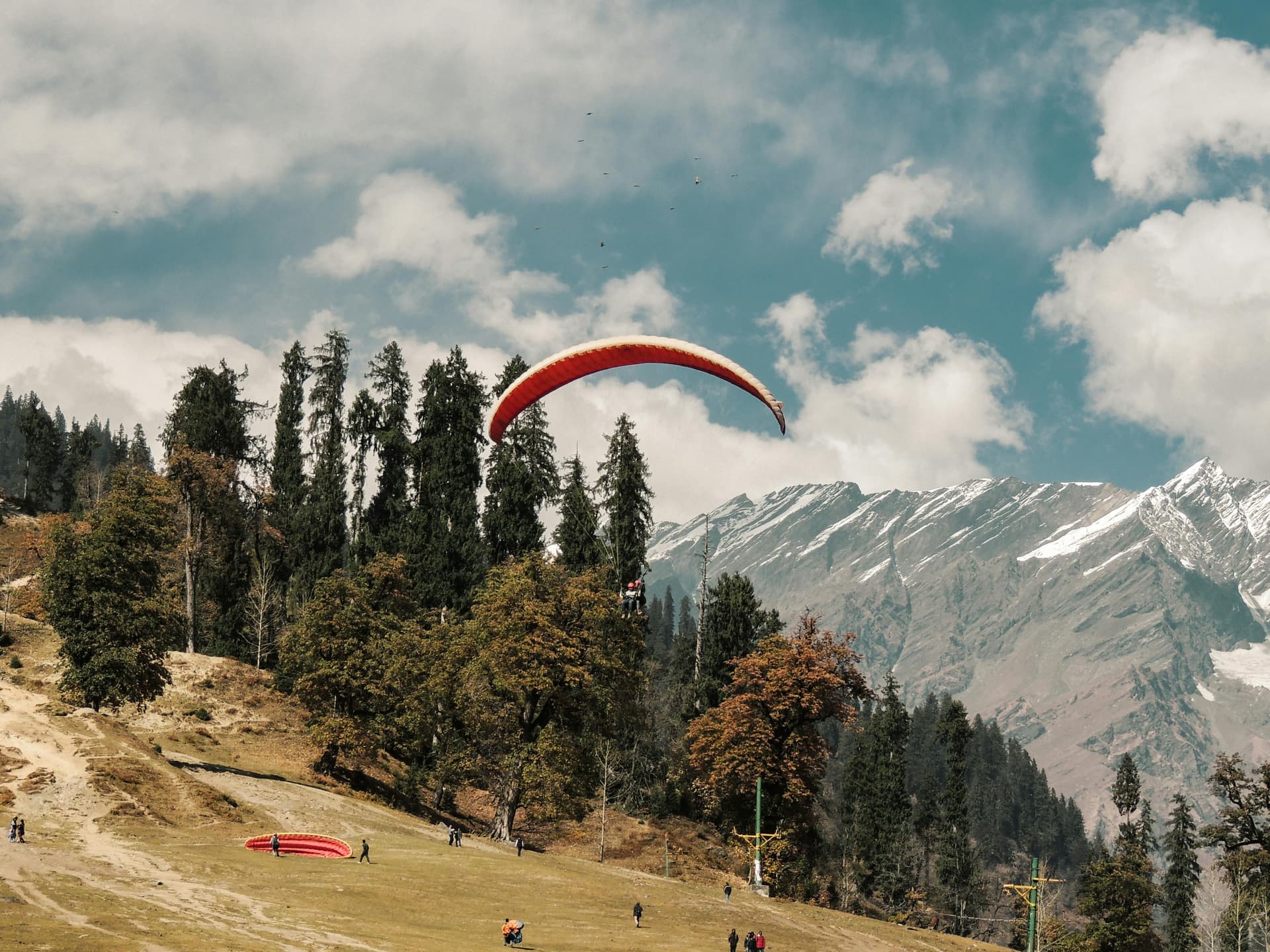 Paragliders soaring over Solang Valley with snow-capped Himalayan peaks in the background